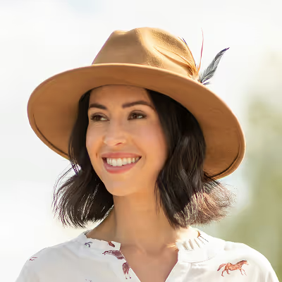 Woman wearing a tan hat with a feather against a blurred natural background